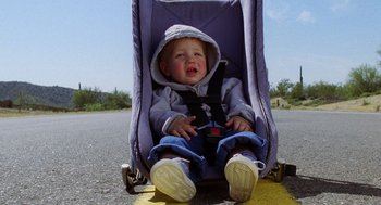 Movie still from “Raising Arizona” (1987), directed by Joel Coen – A baby in a stroller sitting on the ground; Close Up shot, High angle