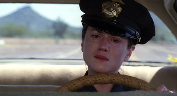 Movie still from “Raising Arizona” (1987), directed by Joel Coen – A police officer sitting in the back seat of a car; Close Up shot, Over the shoulder angle