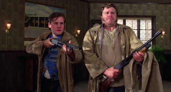 Movie still from “Raising Arizona” (1987), directed by Joel Coen – A man and a woman holding guns in a room; Medium shot, Low angle