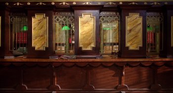 Movie still from “Raising Arizona” (1987), directed by Joel Coen – A bar with a counter and a window with bars on the wall; Wide shot, Overhead angle