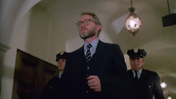 Movie still from “Re-Animator” (1985), directed by Stuart Gordon – A man in a suit and tie standing in front of two other men; Close Up shot, Low angle