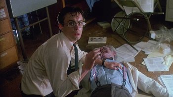 Movie still from “Re-Animator” (1985), directed by Stuart Gordon – A man in a white dress shirt and a tie; Medium shot, Low angle