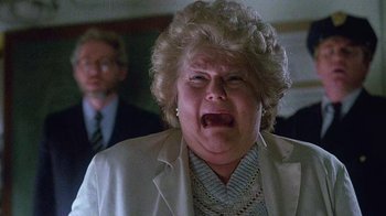 Movie still from “Re-Animator” (1985), directed by Stuart Gordon – An older woman with blonde curly hair is crying in front of a man; Close Up shot, Low angle