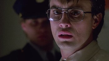 Movie still from “Re-Animator” (1985), directed by Stuart Gordon – A person wearing glasses and a hat; Close Up shot, Low angle