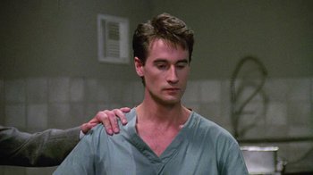 Movie still from “Re-Animator” (1985), directed by Stuart Gordon – A man in a hospital gown is holding another man's arm; Close Up shot, Over the shoulder angle