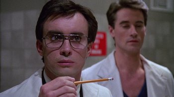 Movie still from “Re-Animator” (1985), directed by Stuart Gordon – A man in a white lab coat holding a pencil; Close Up shot, Low angle
