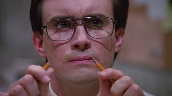 Movie still from “Re-Animator” (1985), directed by Stuart Gordon – A person holding two pencils; Close Up shot, Low angle