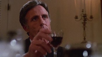 Movie still from “Re-Animator” (1985), directed by Stuart Gordon – A person holding a glass of red wine; Close Up shot, Low angle