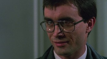 Movie still from “Re-Animator” (1985), directed by Stuart Gordon – A person wearing glasses and a suit; Close Up shot, Low angle