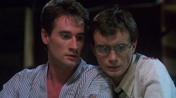Movie still from “Re-Animator” (1985), directed by Stuart Gordon – A couple of men sitting next to each other; Close Up shot, Low angle