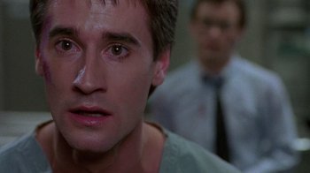 Movie still from “Re-Animator” (1985), directed by Stuart Gordon – A man's face in front of another man in the background; Close Up shot, Low angle
