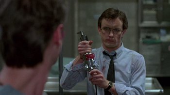 Movie still from “Re-Animator” (1985), directed by Stuart Gordon – A man holding a beer in front of a bathroom mirror; Close Up shot, Low angle