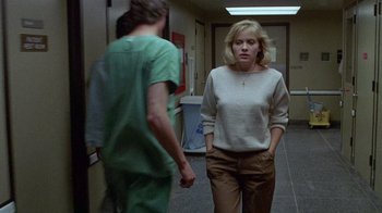 Movie still from “Re-Animator” (1985), directed by Stuart Gordon – A woman is walking in a hallway with a male doctor; Medium shot, Low angle