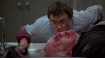 Movie still from “Re-Animator” (1985), directed by Stuart Gordon – A man with a knife in his mouth and a woman with blood on her face; Close Up shot, Low angle