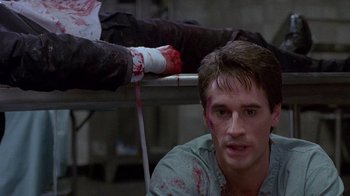 Movie still from “Re-Animator” (1985), directed by Stuart Gordon – A man with blood all over his face and arm; Close Up shot, High angle