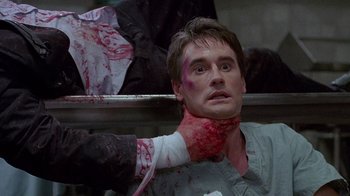 Movie still from “Re-Animator” (1985), directed by Stuart Gordon – A man with blood all over his face and neck; Close Up shot, Over the shoulder angle