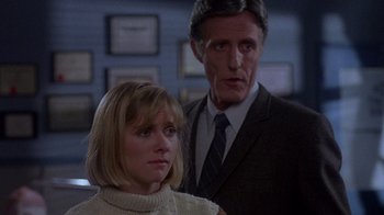 Movie still from “Re-Animator” (1985), directed by Stuart Gordon – A man and a woman standing next to each other in a room; Close Up shot, Low angle