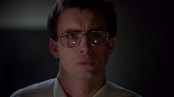 Movie still from “Re-Animator” (1985), directed by Stuart Gordon – A person wearing glasses and a white shirt; Close Up shot, Low angle