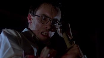Movie still from “Re-Animator” (1985), directed by Stuart Gordon – A man holding a hammer in a dark room; Close Up shot, Low angle