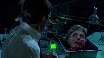 Movie still from “Re-Animator” (1985), directed by Stuart Gordon – A man looking at a zombie in a box; Close Up shot, Over the shoulder angle