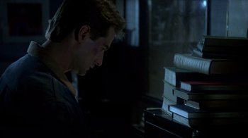 Movie still from “Re-Animator” (1985), directed by Stuart Gordon – A young man looking at a stack of books; Close Up shot, Low angle
