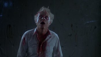 Movie still from “Re-Animator” (1985), directed by Stuart Gordon – A man with blood all over his face and head; Medium shot, Low angle