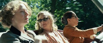 Movie still from “Reaching for the Moon” (2013), directed by Bruno Barreto – A woman with sunglasses is sitting in the back of a car; Close Up shot, Over the shoulder angle