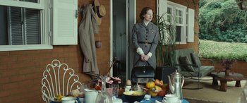 Movie still from “Reaching for the Moon” (2013), directed by Bruno Barreto – A woman standing in front of a table filled with food; Medium shot, Over the shoulder angle