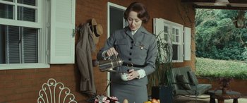 Movie still from “Reaching for the Moon” (2013), directed by Bruno Barreto – A woman in a gray uniform pouring something into a bowl; Medium shot, Low angle