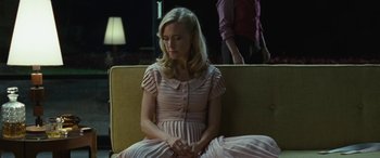 Movie still from “Reaching for the Moon” (2013), directed by Bruno Barreto – A woman in a pink dress sitting on a yellow couch; Medium shot, Over the shoulder angle