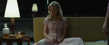 Movie still from “Reaching for the Moon” (2013), directed by Bruno Barreto – A woman in a pink dress sitting on a yellow couch; Medium shot, High angle