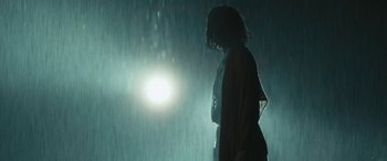 Movie still from “Reaching for the Moon” (2013), directed by Bruno Barreto – A woman standing in front of a light in the rain; Medium shot, Low angle