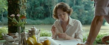 Movie still from “Reaching for the Moon” (2013), directed by Bruno Barreto – A woman sitting at a table with a plate of food; Medium shot, Over the shoulder angle