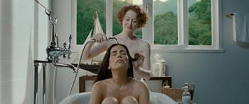 Movie still from “Reaching for the Moon” (2013), directed by Bruno Barreto – A woman is getting her hair blow - dried by another woman in a bath tub; Medium shot, Over the shoulder angle