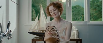 Movie still from “Reaching for the Moon” (2013), directed by Bruno Barreto – A woman standing next to a man in front of a sailboat; Close Up shot, Over the shoulder angle