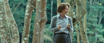 Movie still from “Reaching for the Moon” (2013), directed by Bruno Barreto – A woman standing next to a tree in the woods; Medium shot, Over the shoulder angle