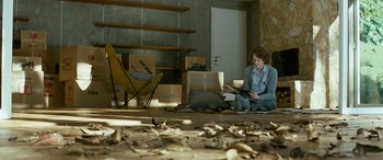 Movie still from “Reaching for the Moon” (2013), directed by Bruno Barreto – A woman sitting on the floor in a room with boxes; Wide shot, High angle