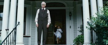 Movie still from “Reaching for the Moon” (2013), directed by Bruno Barreto – An old man standing in front of a young girl on a porch; Wide shot, Low angle