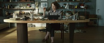 Movie still from “Reaching for the Moon” (2013), directed by Bruno Barreto – A woman sitting at a table in a room; Medium shot, High angle