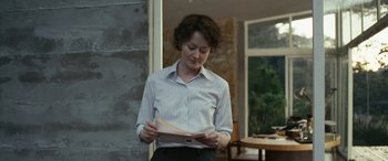 Movie still from “Reaching for the Moon” (2013), directed by Bruno Barreto – A woman standing in front of a wall reading a piece of paper; Medium shot, Over the shoulder angle