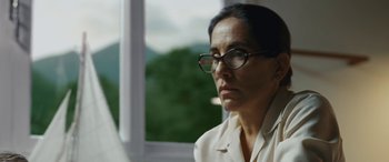 Movie still from “Reaching for the Moon” (2013), directed by Bruno Barreto – A woman wearing glasses looking out of a window; Close Up shot, Low angle