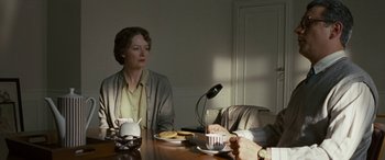Movie still from “Reaching for the Moon” (2013), directed by Bruno Barreto – A woman sitting at a table in front of two people; Medium shot, Over the shoulder angle