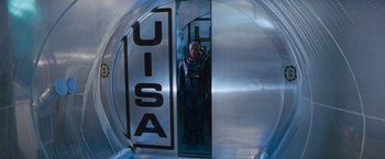 Movie still from “Red Planet” (2000), directed by Antony Hoffman – A man in a space suit standing in a door way; Wide shot, Overhead angle