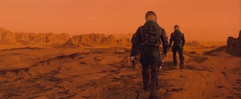 Movie still from “Red Planet” (2000), directed by Antony Hoffman – A man in a space suit walking across a barren landscape; Wide shot, Low angle