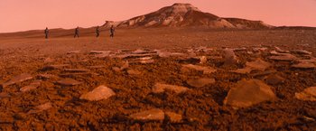 Movie still from “Red Planet” (2000), directed by Antony Hoffman – Two people are flying a kite in the desert; Extreme Wide shot, High angle