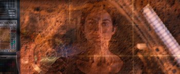 Movie still from “Red Planet” (2000), directed by Antony Hoffman – A woman is looking at the camera with a blurry image of her face; Close Up shot, Overhead angle