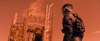 Movie still from “Red Planet” (2000), directed by Antony Hoffman – A man in a uniform standing in front of a construction site; Medium shot, Low angle