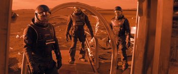 Movie still from “Red Planet” (2000), directed by Antony Hoffman – A group of people standing next to each other on a field; Wide shot, High angle