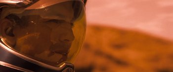 Movie still from “Red Planet” (2000), directed by Antony Hoffman – A man wearing a motorcycle helmet with a sunset in the background; Close Up shot, Low angle