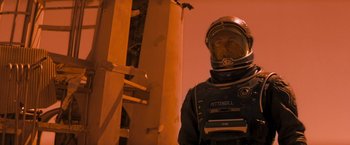 Movie still from “Red Planet” (2000), directed by Antony Hoffman – A man in a space suit standing next to a building; Medium shot, Over the shoulder angle